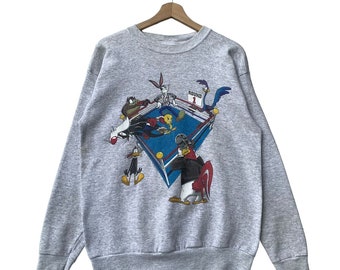 May include: A gray sweatshirt with a vintage cartoon print of Bugs Bunny, Tweety Bird, Sylvester the Cat, Daffy Duck, and Road Runner in a boxing ring. The print says "Round 1".