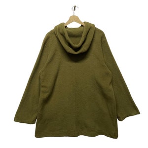 K&ouml;nnte beinhalten: Ein lang&auml;rmliger Kapuzenpullover in einem ged&auml;mpften Olivgr&uuml;n. Der Pullover hat eine lockere Passform und ein schlichtes Design.