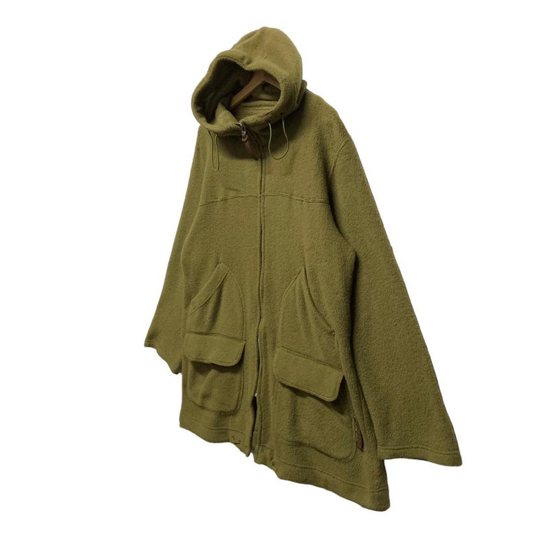 K&ouml;nnte beinhalten: Eine gr&uuml;ne Kapuzenjacke mit Rei&szlig;verschluss und mehreren Taschen. Die Jacke ist aus einem weichen, strukturierten Stoff.