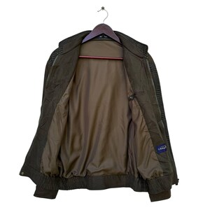 May include: A brown and green plaid jacket with a zipper closure. The jacket has a brown lining and a blue label that says "L'Estrange".