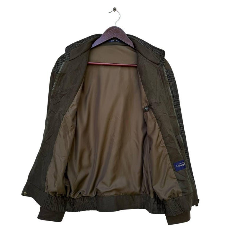 May include: A brown and green plaid jacket with a zipper closure. The jacket has a brown lining and a blue label that says "L'Estrange".