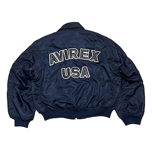 Vintage Avirex MA 1 Bomber Jacket Navy USA Flight Jacket 90s Streetwear Military Jacket Classic Zip Up Nylon Bomber Coat For Men And Women Rare Avirex USA Outerwear Piece With Iconic Back Logo Design.