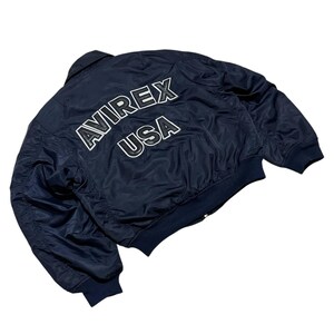 Vintage Avirex MA 1 Bomber Jacket Navy USA Flight Jacket 90s Streetwear Military Jacket Classic Zip Up Nylon Bomber Coat For Men And Women Rare Avirex USA Outerwear Piece With Iconic Back Logo Design.