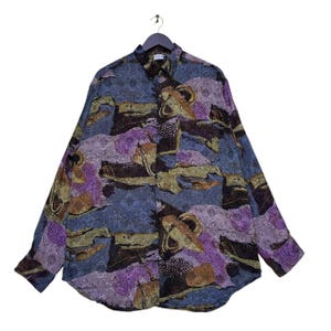 May include: A long-sleeved button-up shirt with an abstract print in shades of purple, blue, brown, and gold.