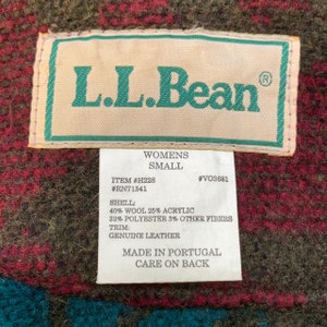 May include: A brown, green, and red plaid L.L.Bean jacket tag with the text "Womens Small" and the details "Item #H228 #RN71341 #VO3681" and the fabric composition "Shell: 40% Wool 25% Acrylic 32% Polyester 3% Other Fibers Trim: Genuine Leather" and the text "Made in Portugal Care on Back".