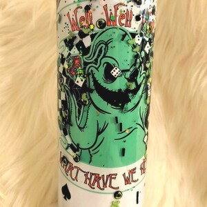 Może przedstawiać: Zielony i biały kubek z błyszczącym wykończeniem. Kubek przedstawia postać z kresk&oacute;wki z przebiegłym uśmiechem i tekstem "Well Well Well What Have We Here".