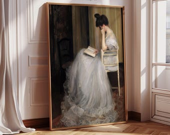 May include: A framed vintage art print featuring a woman in a long, light blue dress seated in a chair, reading a book. The artwork has a gold frame and the text "VIVID ART SPACE Printable Vintage Art" at the top.