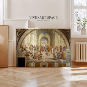 May include: A framed print of a Renaissance-era painting, featuring a large group of figures in classical attire within an arched architectural setting. The artwork is in a wooden frame and leans against a wall. The text "VIVID ART SPACE Printable Vintage Art" is at the top.
