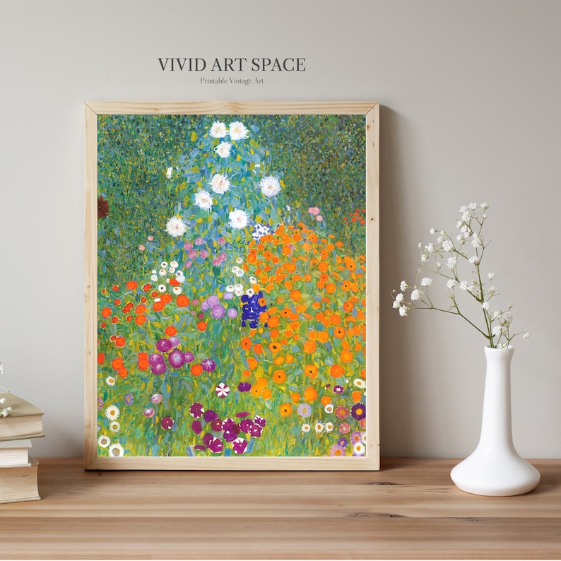 May include: A framed print of a colorful garden scene with vibrant orange, purple, and white flowers. The artwork, in a light wood frame, is labeled "VIVID ART SPACE Printable Vintage Art". A white vase with flowers sits on a wooden surface.