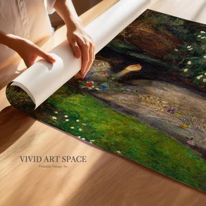 May include: A rolled art print being unrolled, displaying a vintage painting of a woman in a stream. The artwork shows a green landscape with flowers and a warm colour palette. The text "VIVID ART SPACE" and "Printable Vintage Art" is visible.
