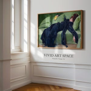 May include: A framed vintage art print depicting a woman in a black dress resting on a green sofa. The artwork has a gold frame and is displayed on a white wall. The text "VIVID ART SPACE" is printed below the artwork.