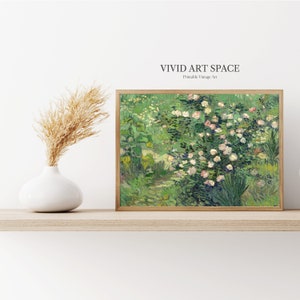 Puede incluir: Una impresi&oacute;n enmarcada de una escena de jard&iacute;n con rosas rosas y follaje verde. La obra de arte est&aacute; en un marco de madera y se exhibe en un estante de color claro. Un jarr&oacute;n blanco con hierba de la pampa seca est&aacute; a la izquierda de la obra de arte. El texto "VIVID ART SPACE" est&aacute; en la parte superior.