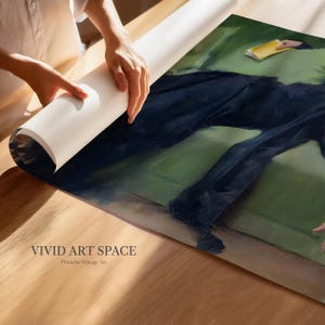 May include: A person unrolling a rolled-up print of a vintage painting. The artwork depicts a figure in dark clothing on a green background. The text "VIVID ART SPACE Printable Vintage Art" is visible on the print.