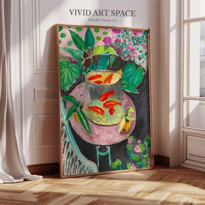 May include: A painting of a bowl of goldfish with green plants and flowers in the background. The bowl is on a pink table with a black background. The painting is in a gold frame.