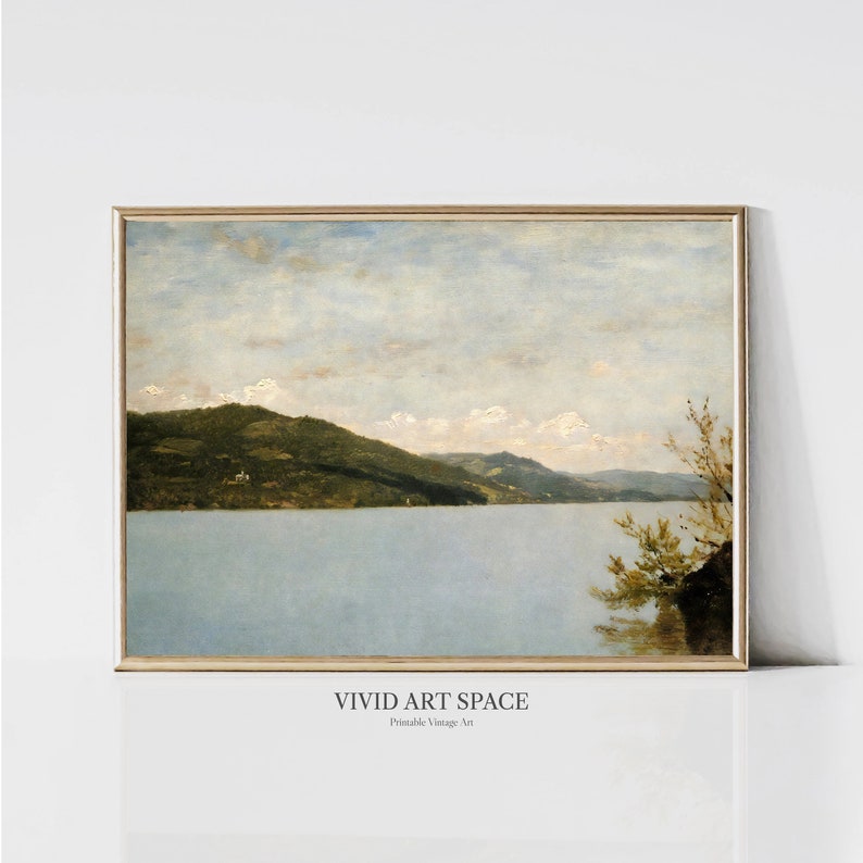 Pu&ograve; includere: Un dipinto vintage di una scena di lago con una catena montuosa sullo sfondo. Il cielo &egrave; di un azzurro chiaro con nuvole bianche. Il lago &egrave; di un azzurro chiaro e le montagne sono di un verde scuro. Il dipinto &egrave; incorniciato in una cornice di legno chiaro.