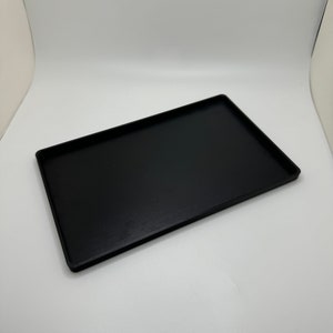 Peut inclure: Un plateau rectangulaire noir en plastique. Le plateau est lisse et a une finition mate.