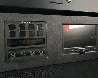 May include: A black Stream Deck with a small LCD screen and four knobs. The Stream Deck has a grid of nine buttons. The screen displays the text "tc electronic".