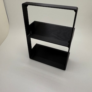 Könnte beinhalten: Ein schwarzes Metallregal mit zwei Ablagen. Das Regal ist aus Metall und hat ein schlichtes, modernes Design.