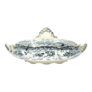 May include: A white and blue ceramic serving dish with a lid. The dish features a floral pattern and gold trim. The handles are curved and the lid has a decorative handle. A classic piece for serving food.