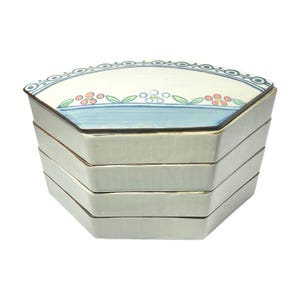 May include: A set of four white ceramic stacking bowls with a blue and green floral design on the top bowl. The bowls are octagonal in shape and have a slightly rounded edge.