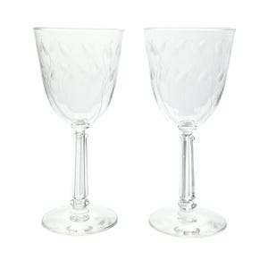 May include: Two clear wine glasses with etched leaf designs. The glasses have a classic shape with a rounded bowl, a long stem, and a circular base. The leaf pattern adds a touch of elegance to the glassware.