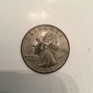 Może przedstawiać: Srebrna amerykańska moneta o wartości ćwierć dolara z datą 1978 na dole i napisami "Liberty" i "In God We Trust" na górze.