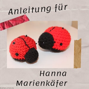 May include: Two crocheted ladybug toys with red and black bodies and black bead eyes. The text "Hanna Marienkäfer" is below the toys.
