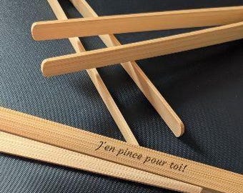 Op de afbeelding: Houten tang met een natuurlijke afwerking, met een eenvoudig ontwerp. De tekst "J'en pince pour toi!" is gegraveerd op een van de tangen. De tangen zijn gemaakt van lichtgekleurd hout en staan tegen een donkere achtergrond.