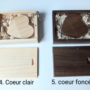 Op de afbeelding: Twee houten hartvormige sleutelhangers in dozen. De sleutelhanger links is van licht hout en de sleutelhanger rechts is van donker hout. Beide sleutelhangers zitten in hun eigen dozen met houtsnippers.