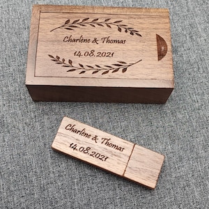Puede incluir: Una caja de madera y una memoria USB de madera con el texto "Charlene & Thomas 14.08.2021" grabado en ellas.