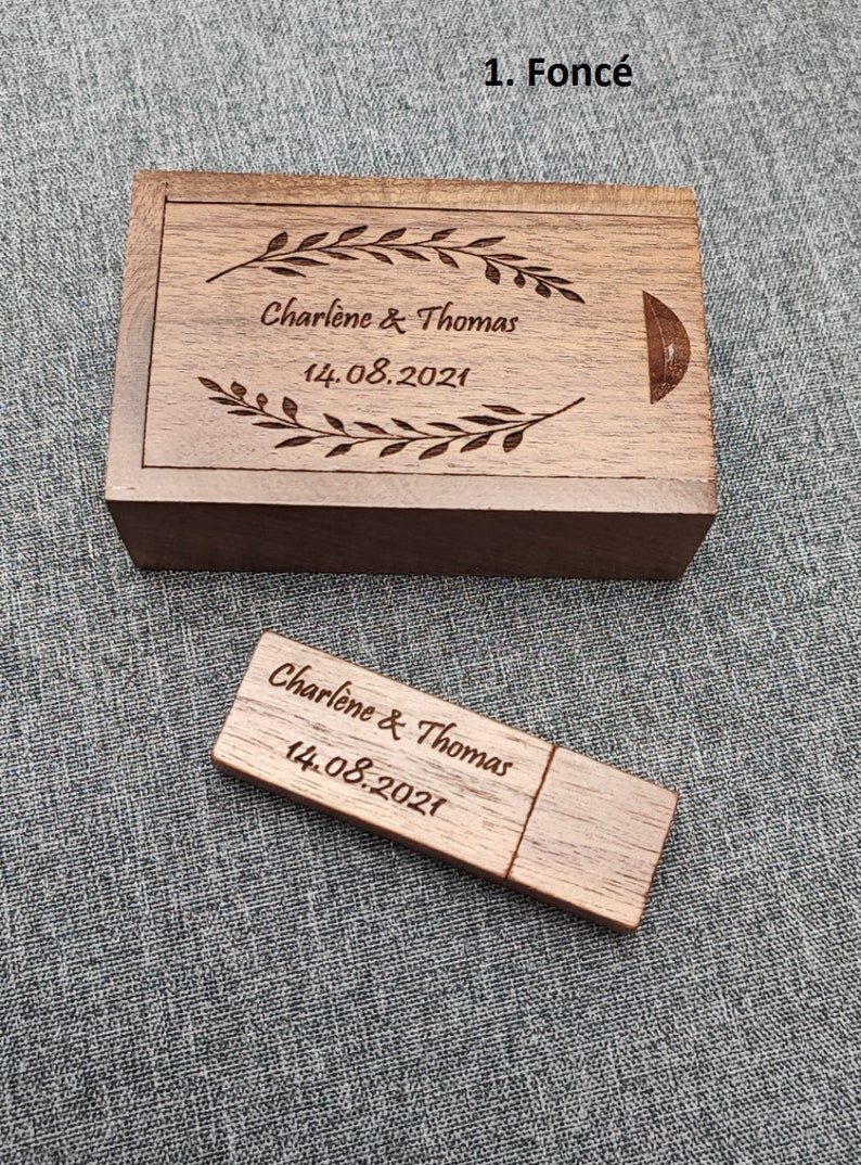 Op de afbeelding: Een houten doos en een houten USB-stick met de tekst "Charlene & Thomas 14.08.2021" erop gegraveerd.