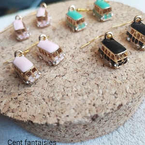 Peut inclure: Un ensemble de 10 paires de boucles d'oreilles dorées avec un motif de bus miniature. Les bus sont peints dans différentes couleurs, notamment le rose, le noir, le turquoise et le blanc. Les boucles d'oreilles sont parfaites pour ajouter une touche de fantaisie à n'importe quelle tenue.
