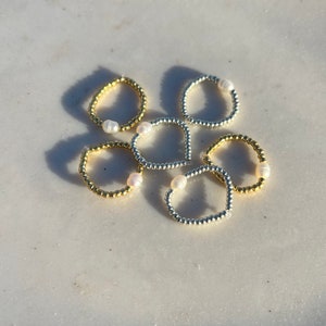 May include: Six beaded rings with a pearl accent. Three rings are gold and three rings are silver.