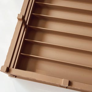 May include: A rectangular, open-top wooden crate with multiple horizontal shelves. The crate is constructed from light brown wood and features a slatted design on the sides. The interior shelves are evenly spaced.