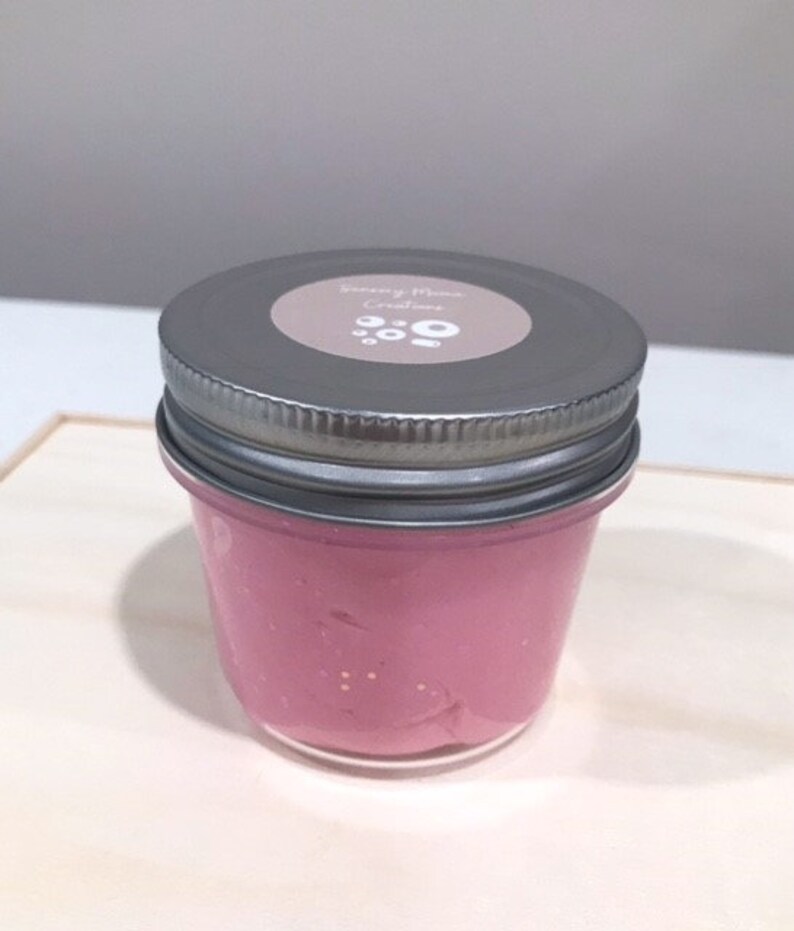 May include: A glass jar filled with pink slime with glitter. The jar has a silver lid with a white label that says "Sleepy Moon Creations".