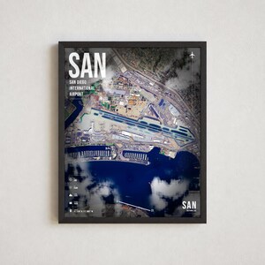May include: A framed aerial map print of San Diego International Airport, labeled SAN. The image features a satellite view of the runway, surrounding infrastructure, and harbor, overlaid with white text, airport codes, and geographic coordinates.