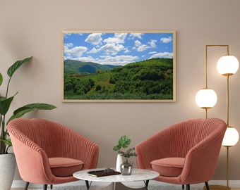 Könnte beinhalten: Zwei rosa Sessel mit einem weißen Couchtisch davor. Ein gerahmtes Landschaftsfoto eines grünen Hügels hängt an der Wand hinter den Sesseln. Eine goldene Stehlampe mit drei weißen Kugelleuchten steht in der Ecke des Raumes.