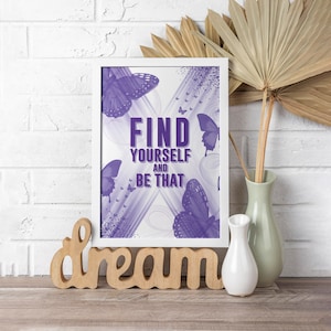 Könnte beinhalten: Lilafarbener und weißer Motivationszitatdruck mit Schmetterlingen und dem Text "Finde dich selbst und sei das". Der Druck ist in einem weißen Rahmen gerahmt und liegt auf einer Holzoberfläche mit einem Holzschild, auf dem "träumen" steht.