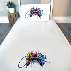 May include: White twin bed sheet set with a colourful video game controller and the name "Gareth" printed on it.