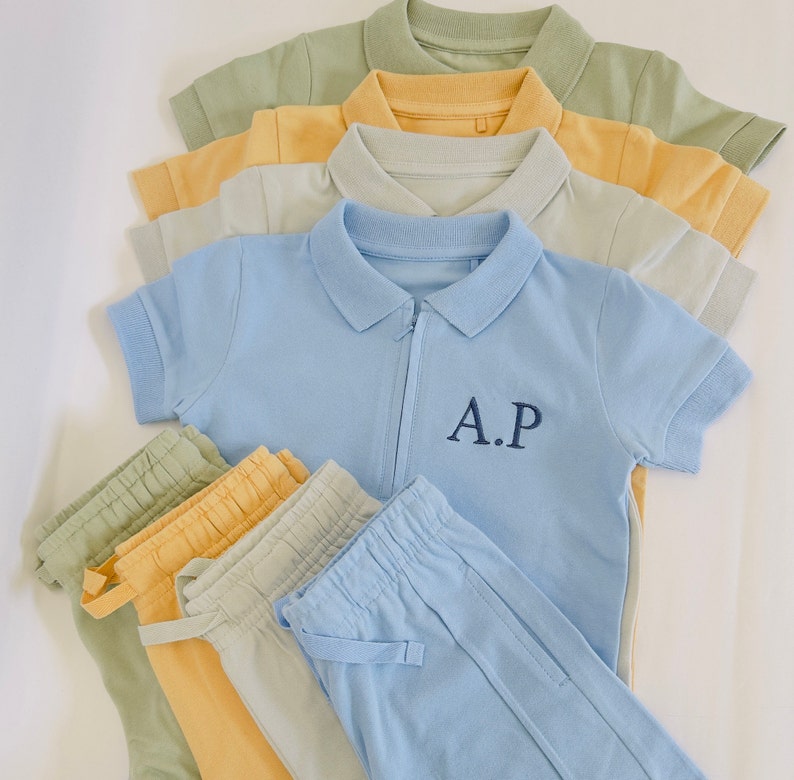 May include: A set of blue, yellow, and green polo shirts and matching pants. The polo shirt has a zipper and the text "A.P." embroidered on the front.