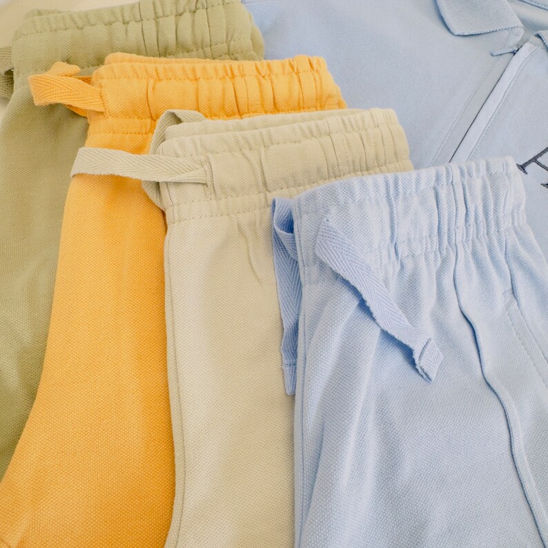 May include: Four pairs of pants in different colors: green, yellow, beige, and light blue. The pants are made of a soft, comfortable fabric and have a drawstring waistband.