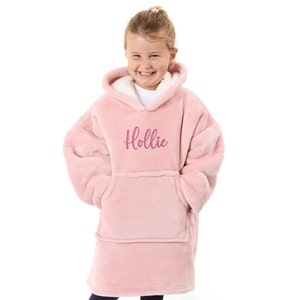 May include: A pink fleece hooded blanket with a large pocket in the front. The blanket has the name "Hollie" embroidered on the front in pink.