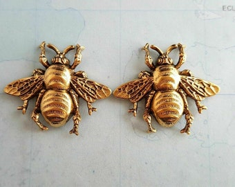 May include: Two gold-toned bee-shaped metal charms with detailed wings and legs.