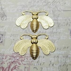 May include: Two gold metal bee charms with detailed wings and a textured body. The bees are approximately 3.8 cm in length.