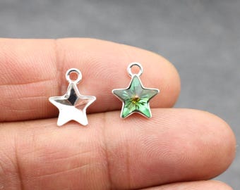 May include: Two silver star-shaped charms, one with a clear glass center and the other with a green glass center.
