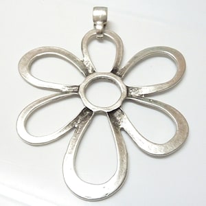 Könnte beinhalten: Ein silberfarbener Metallanhänger in Form einer Blume mit sechs Blütenblättern. Der Anhänger hat oben eine Öse zum Anbringen an einer Kette oder Schnur.