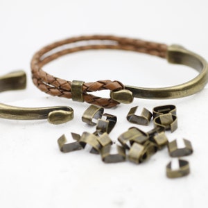 Peut inclure: Un bracelet en cuir marron avec une fermeture en m&eacute;tal et un embout en m&eacute;tal. Le bracelet est entour&eacute; d'un tas de petites fermetures en m&eacute;tal.