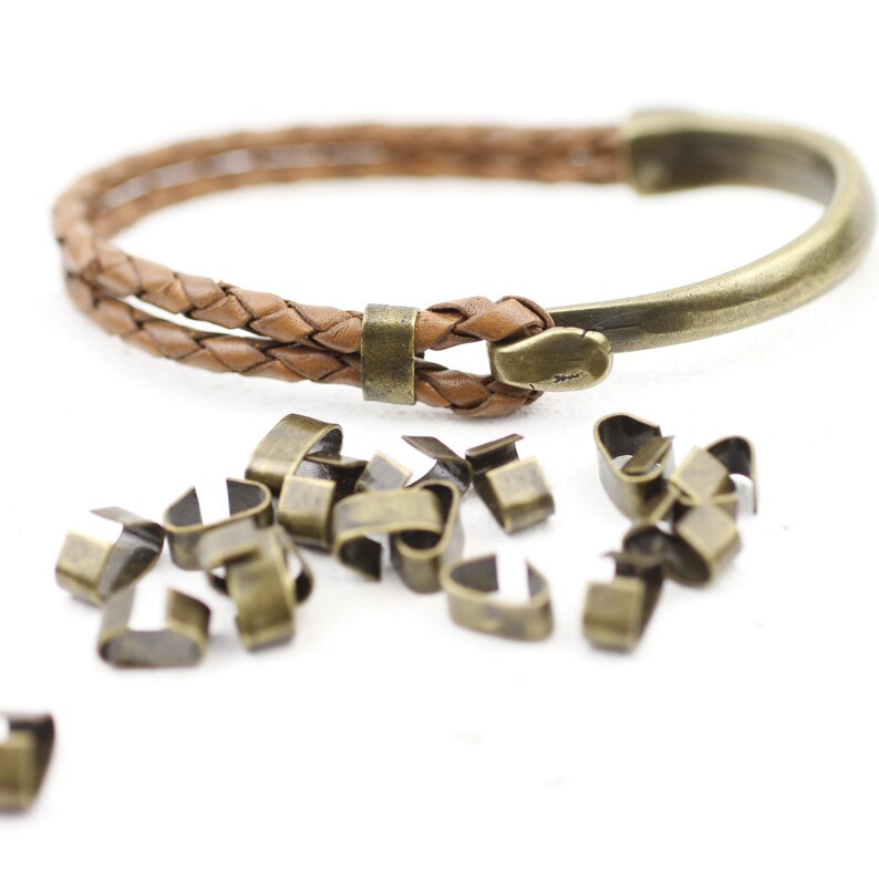 Peut inclure: Un bracelet en cuir marron avec une fermeture en m&eacute;tal et un tas de petites fermetures en m&eacute;tal.