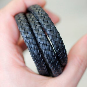 May include: Three strands of black braided leather cord.