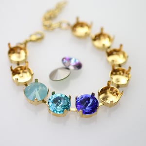 Pode incluir: Um bracelete dourado com uma corrente e várias engastes para pedras de cristal. O bracelete tem um fecho de encaixe. Os engastes estão vazios, exceto por três engastes que têm pedras de cristal azuis e azul claro.